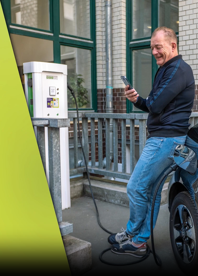 Ein Mann steht an seinem Auto mit seinem Smartphone in der Hand und lädt sein Elektro-Auto.